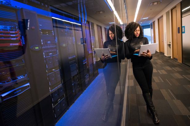 Women in a server room working win a laptop.