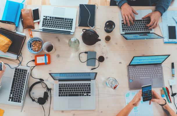 A group of professionals working together at a table, focused on their laptops, improving brand reputation management.