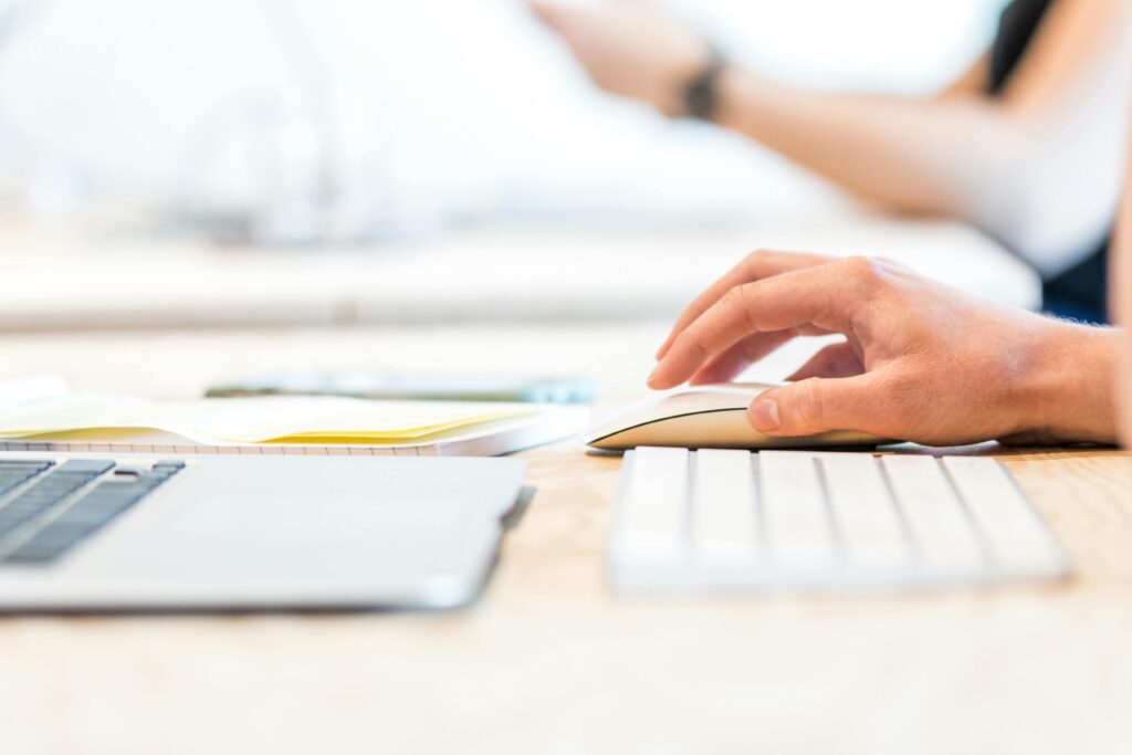 Close-up of a person using a wireless mouse at a modern desk while working on PPC campaign best practices.