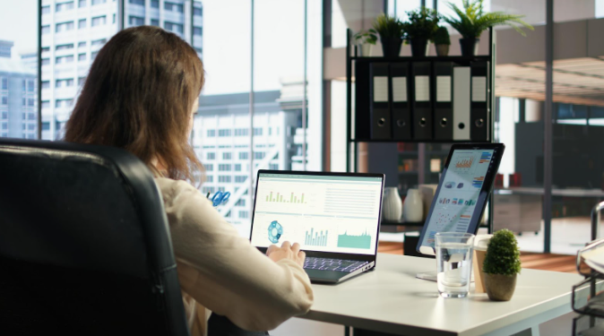 Business professional analyzing data reports on laptop and tablet in modern office to build content authority.